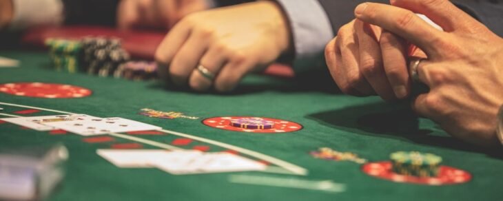 Players' hands with cards and chips on a green blackjack table