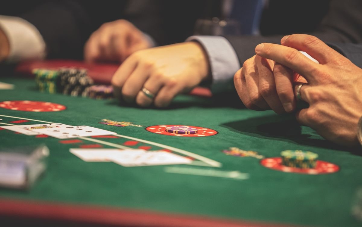 Players' hands with cards and chips on a green blackjack table